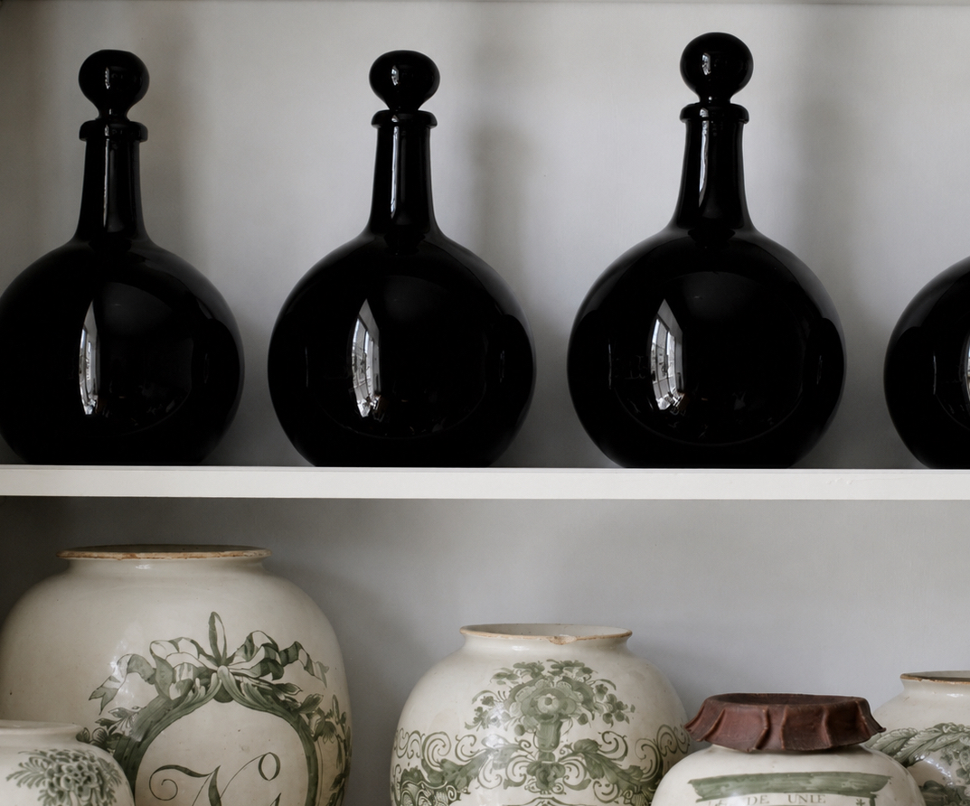 Deep blue glass bottles above green-and-white ceramic jars on open shelves